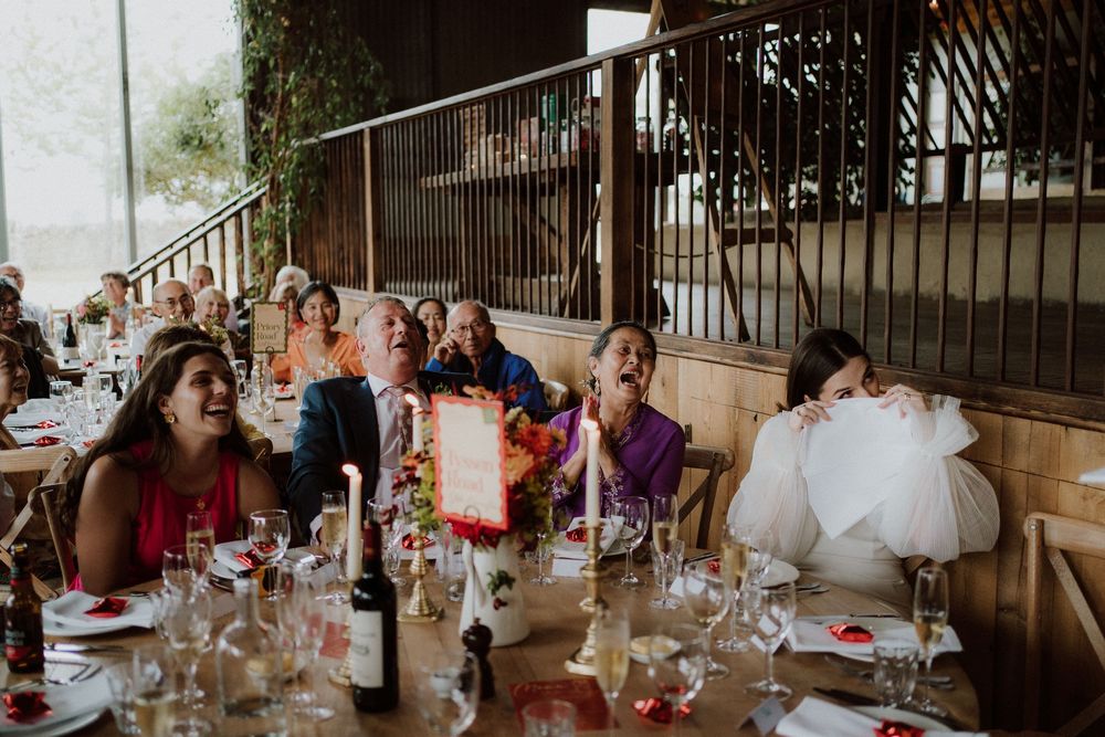 Wedding reception guests share laughter and joy during wedding speeches at Stone Barn, Cotswolds