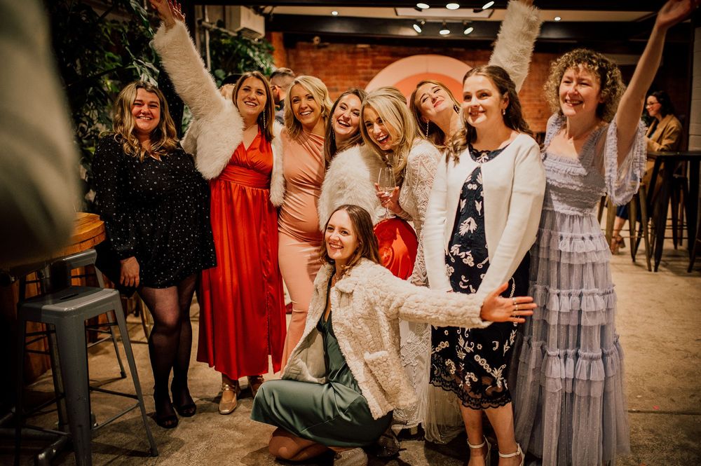 Wedding party celebrates joyfully with dancing and laughter in a rustic barn venue.