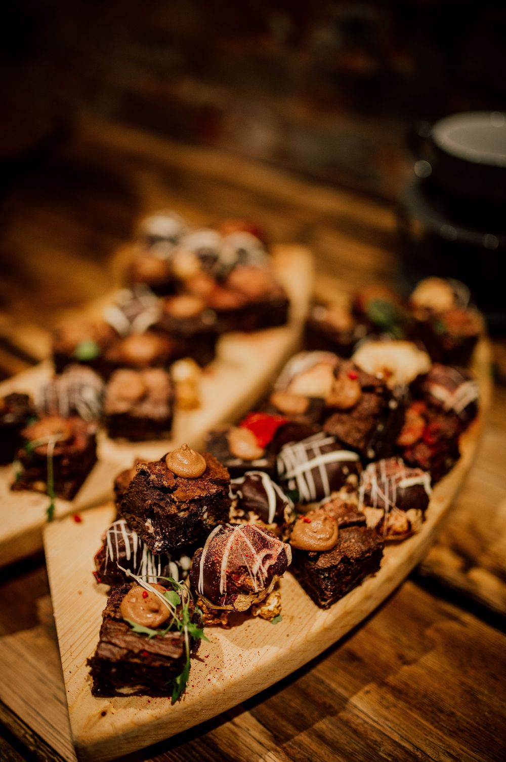 Assorted chocolate desserts and pastries arranged on wooden serving boards in warm lighting.
