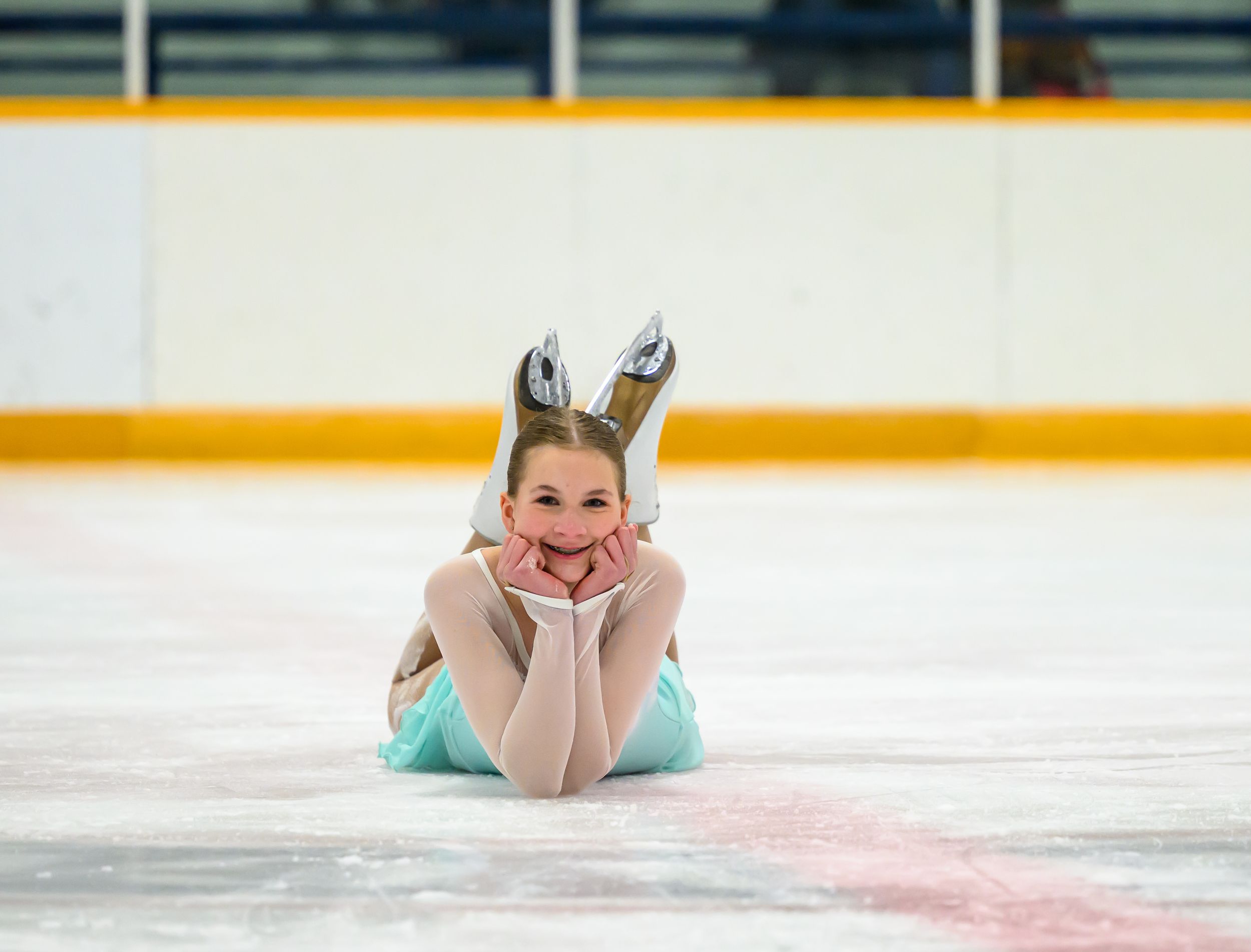 A figure skater performs a graceful pose while lying on the ice during a skating routine.