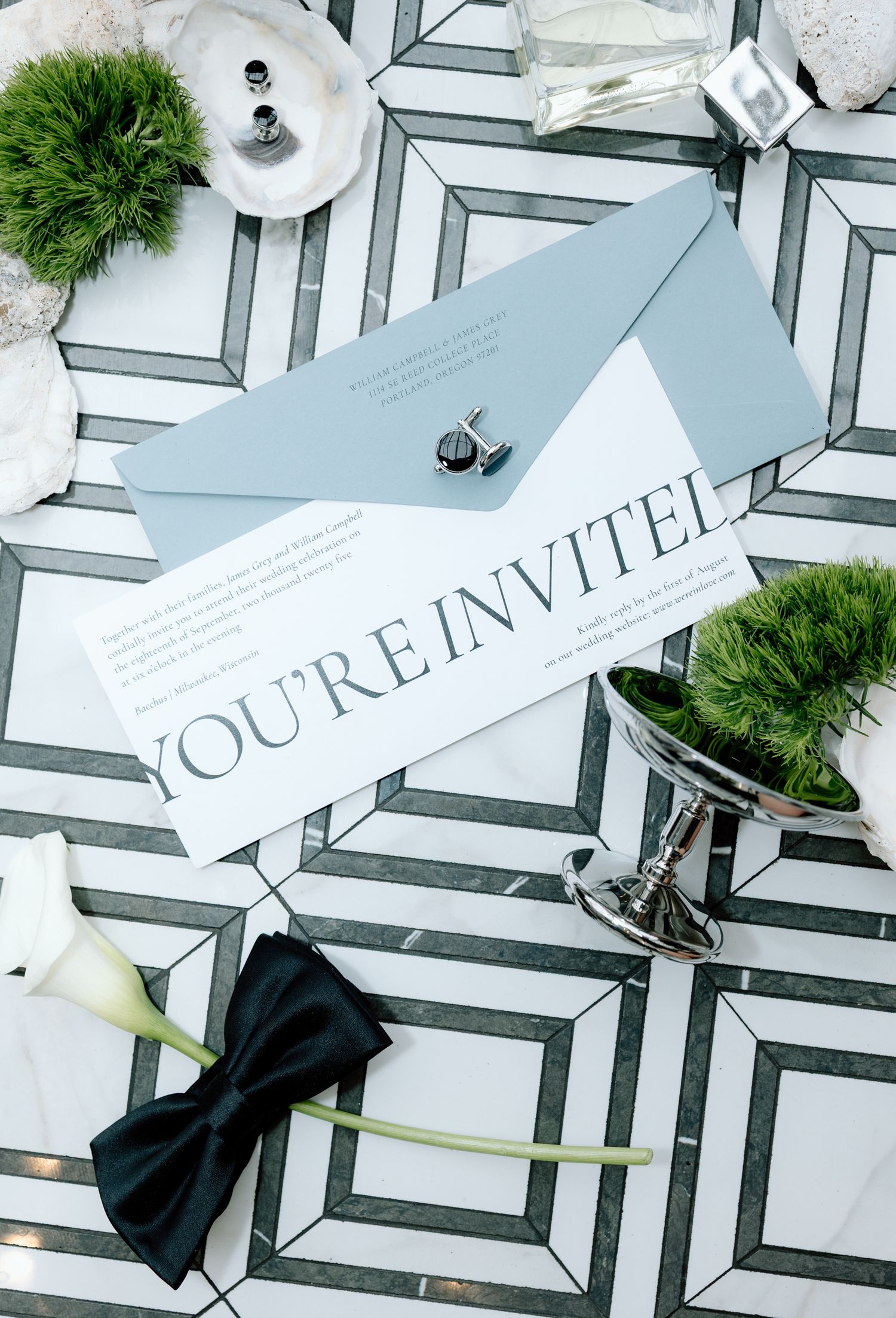 Wedding place cards with black bows and white calla lilies arranged on a geometric patterned surface.