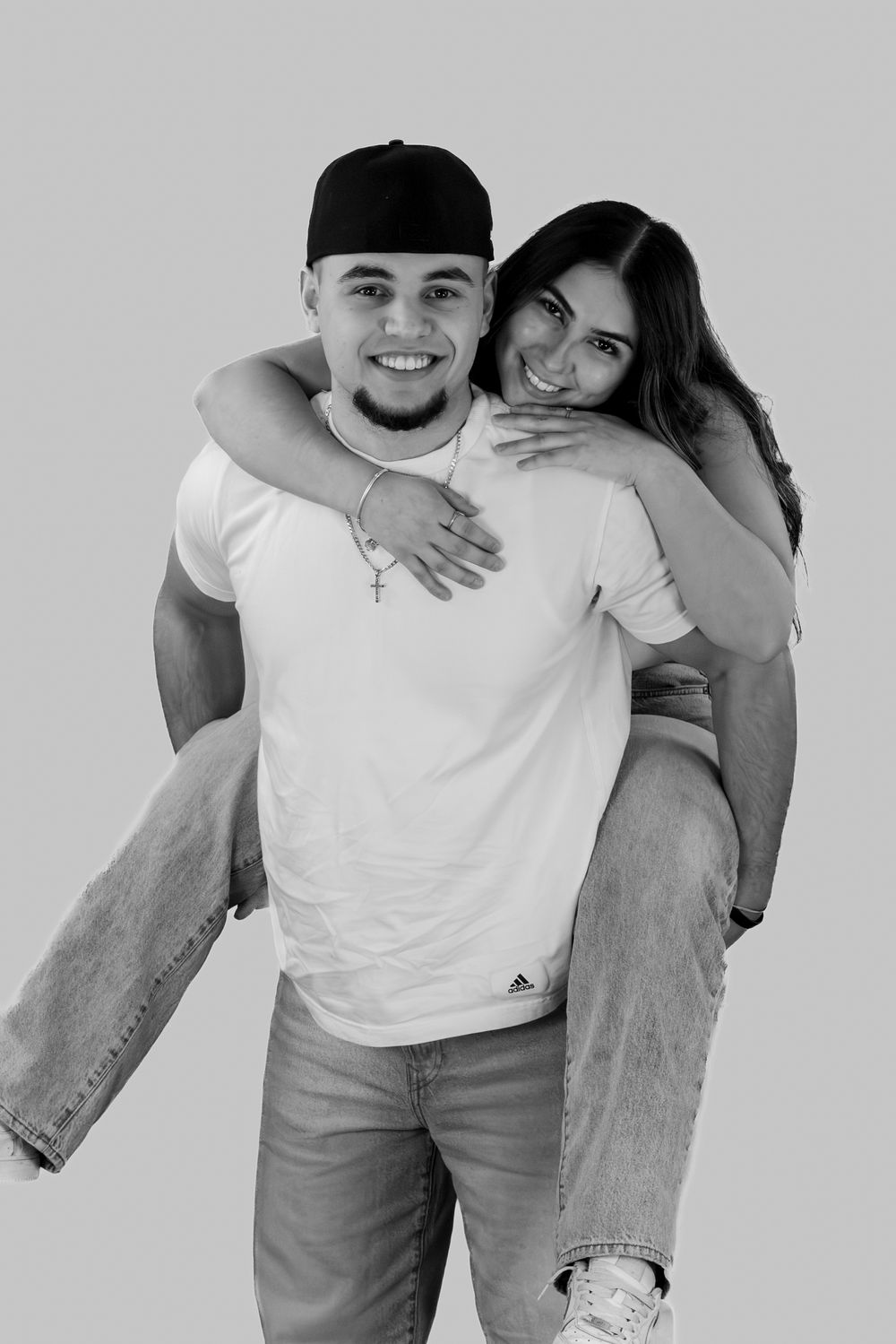 A series of playful black and white couple photos showing affectionate poses in casual white and gray outfits.