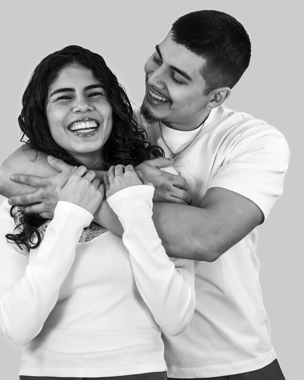A couple shares joyful laughter while embracing in a series of black and white photographs.