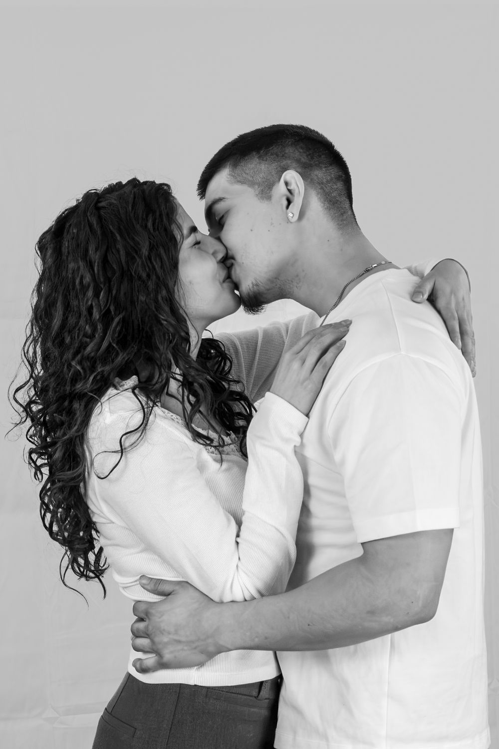 A series of black and white romantic photos showing an intimate embrace between a couple in white clothing.