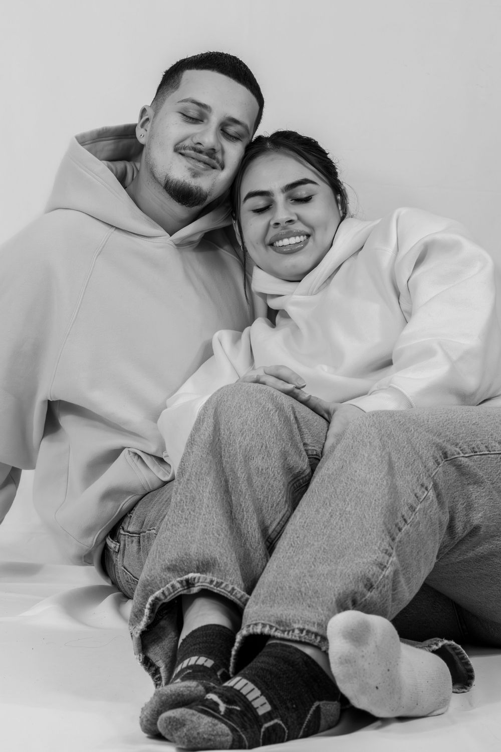 A black and white photo series showing a couple lying down and laughing together while wearing casual clothes.