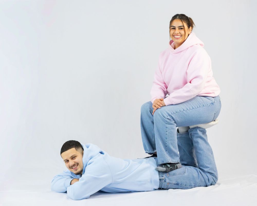 Person in pink sweater and jeans poses playfully on white background in four different positions.