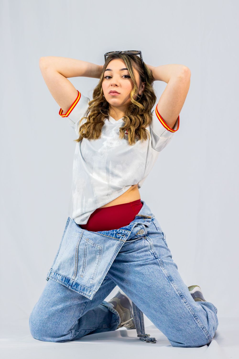 Fashion model in white t-shirt and light blue jeans poses dynamically against white background in photo series.