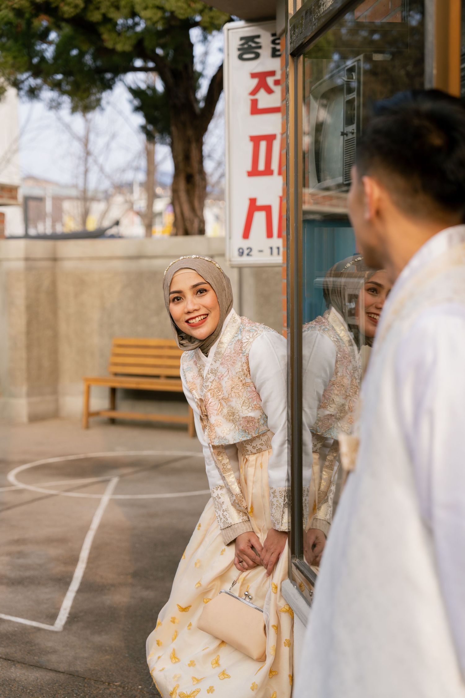 A couple in traditional wedding attire sharing joyful moments during their outdoor photoshoot.
