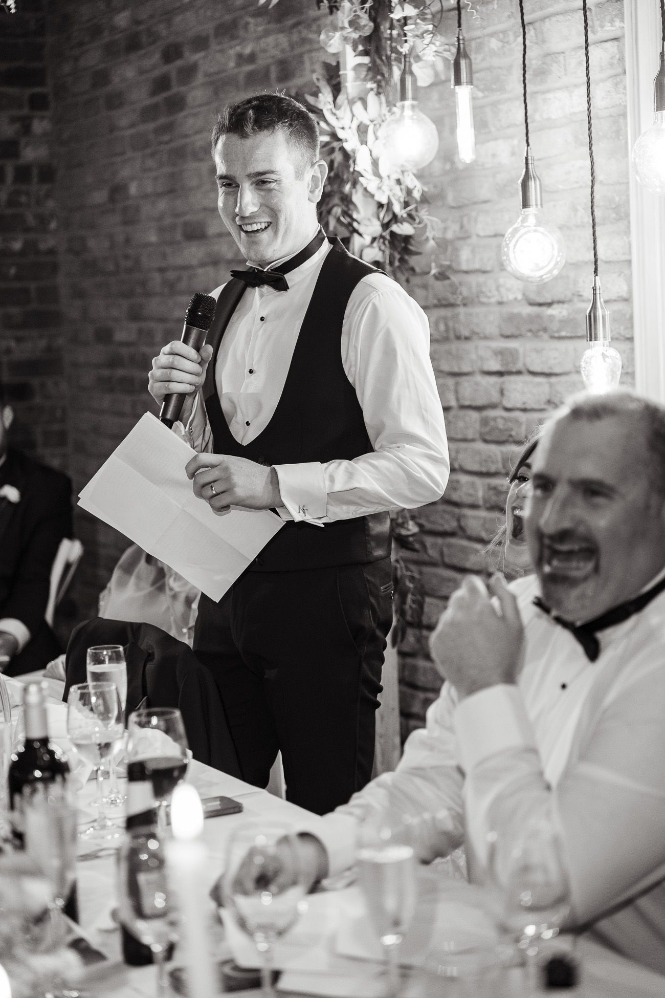 A series of candid moments at a formal dinner event showing a server interacting with guests at a brick-walled venue at Larkspur Lodge