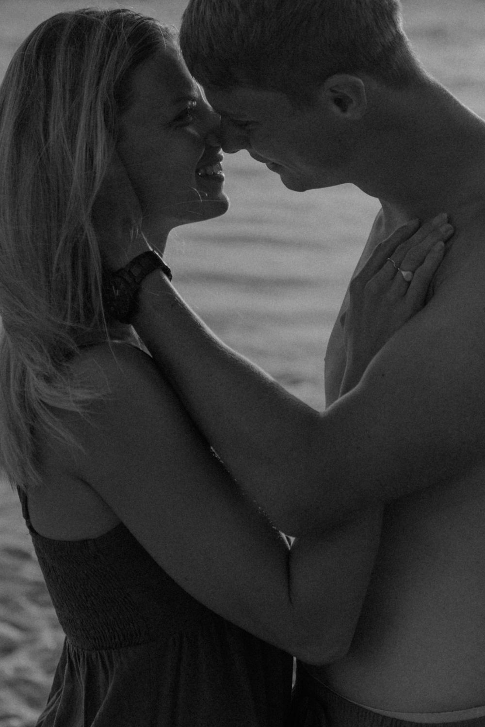 A romantic black and white photo series showing an intimate couple embracing and about to kiss on the beach.