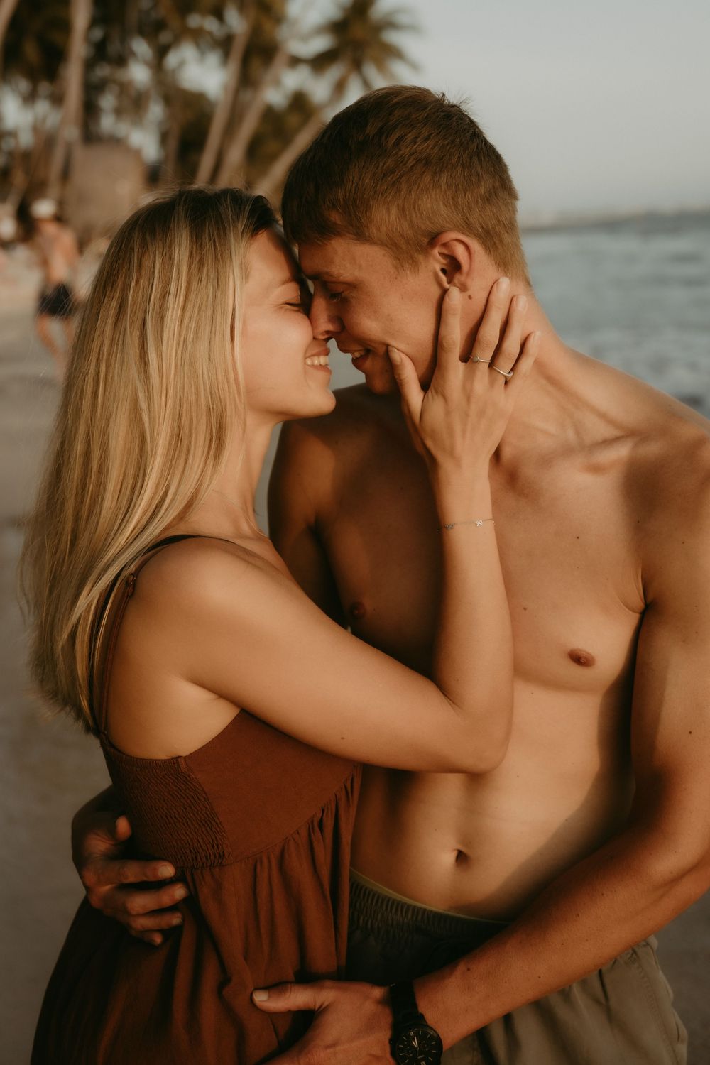 Intimate beachside photoshoot featuring a couple in warm golden light with palm trees visible.