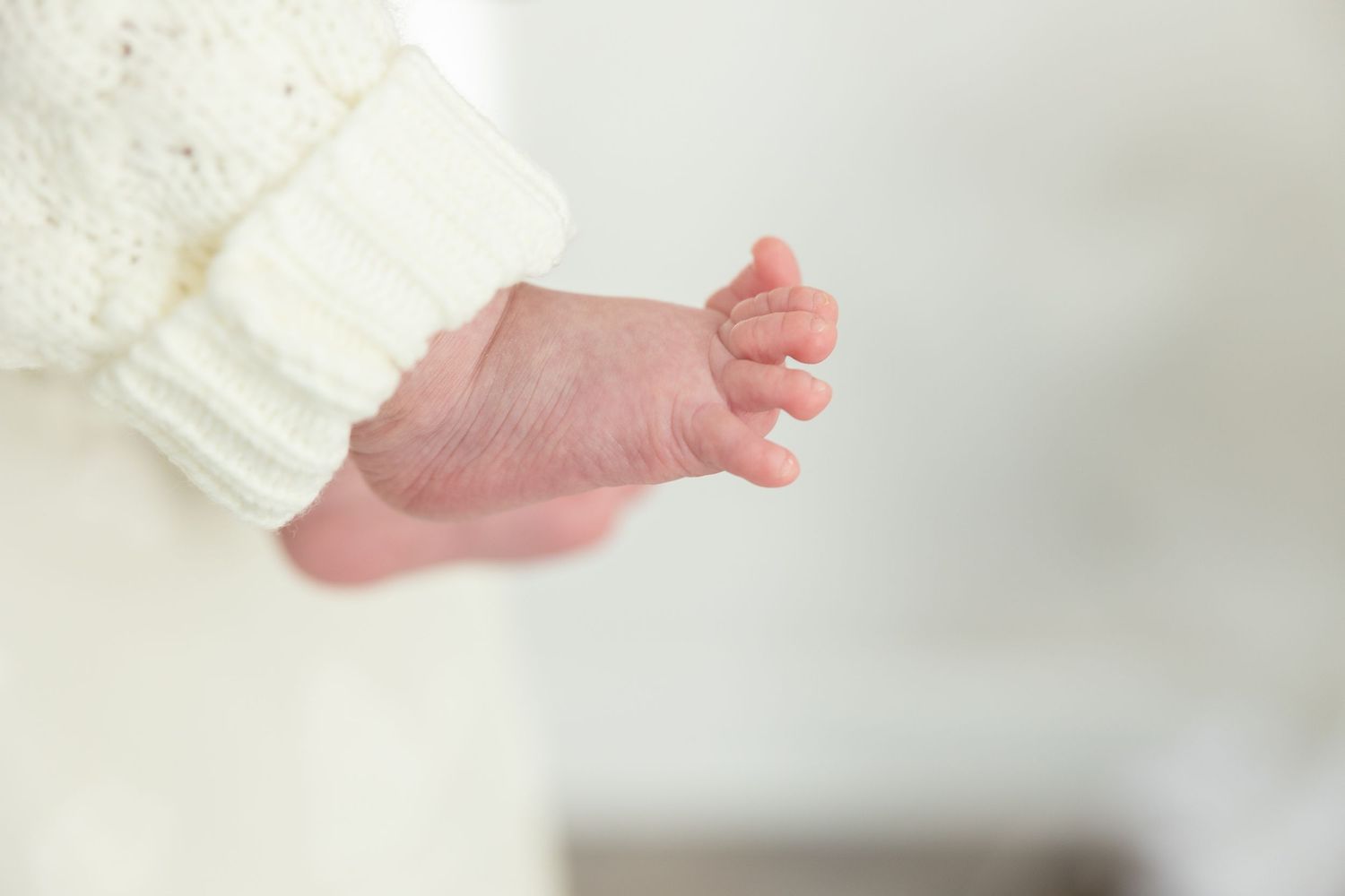 Close-up view of a newborn baby's tiny feet wrapped in soft white blankets.