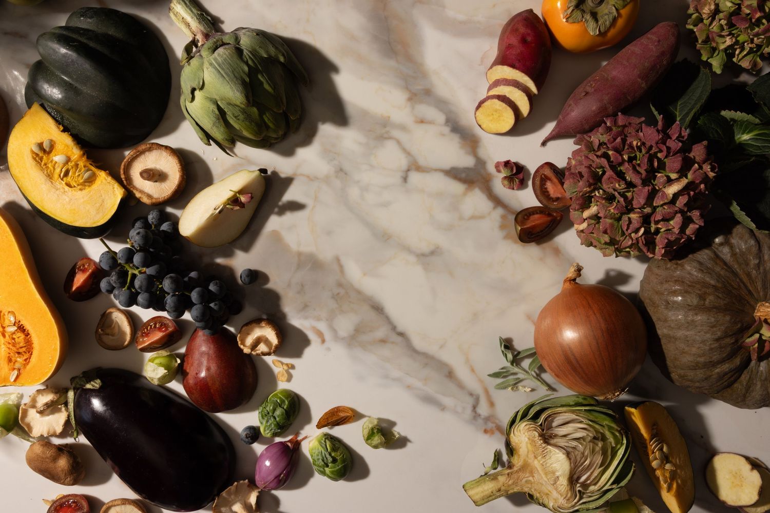 Late Autumn Harvest. Variety of fall produce: eggplant, sweet potato, acorn squash, artichoke, pumpkin, mushroom, and pear.