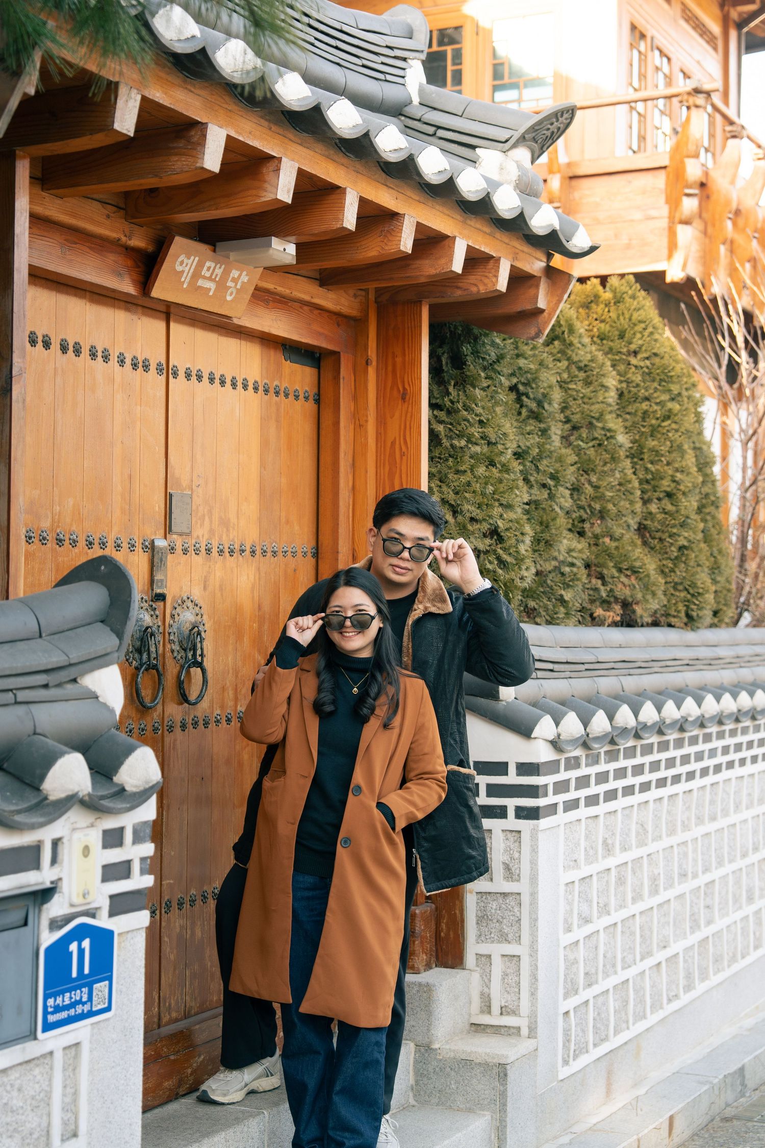 Tourists exploring traditional Korean architecture with ornate tiled roofs and white stone walls in winter.
