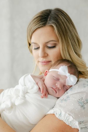 A peaceful portrait of a sleeping newborn being cradled in soft white clothing.