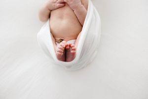 A series of minimalist white photos showing close-up details of a newborn baby's delicate features and tiny body parts.