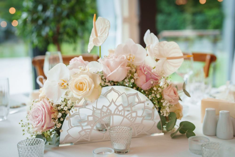 Elegant wedding reception table decorated with pink and white roses, candles and delicate floral arrangements.