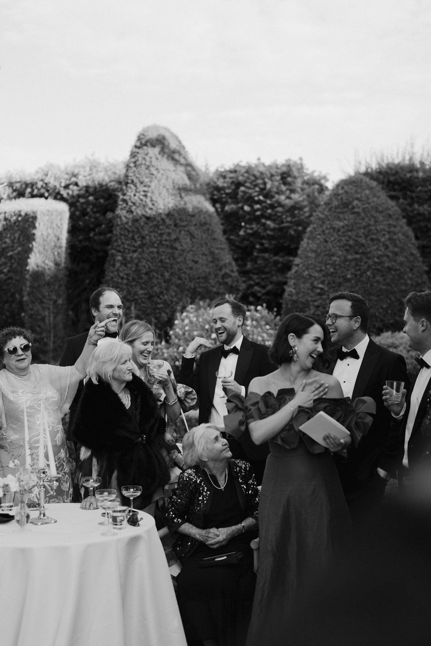 wedding guests laughing at father of the brides speech on the lawn at dewsall court in herefordshire