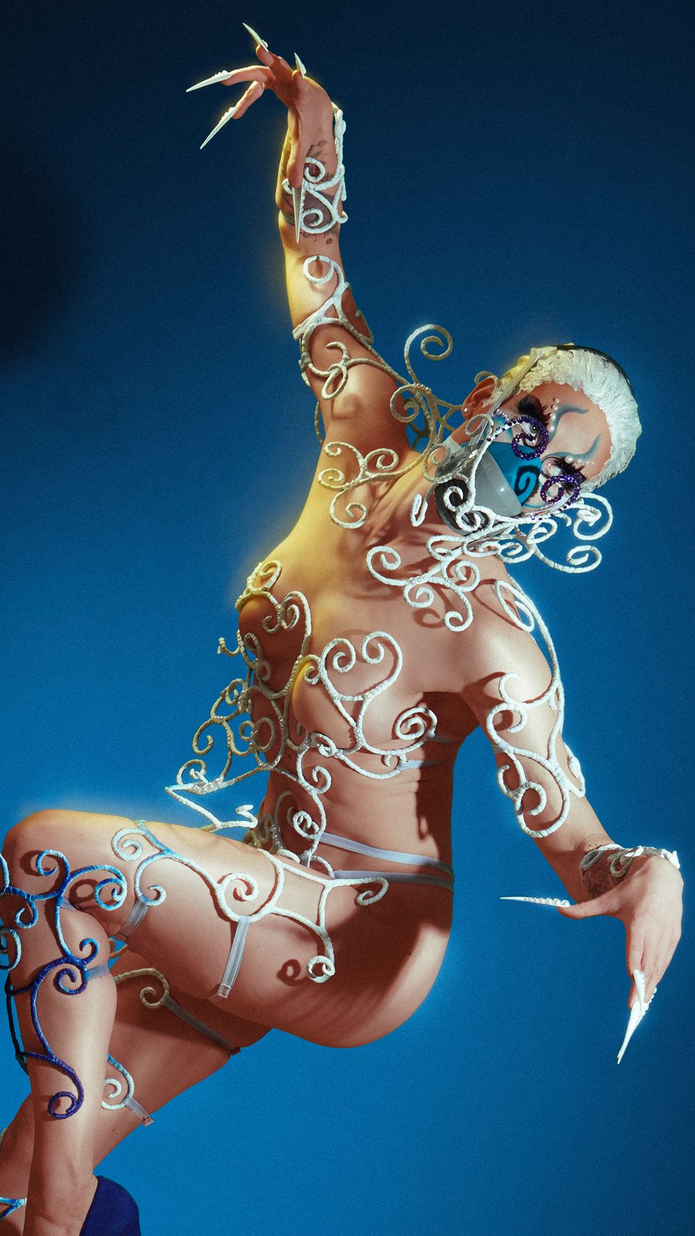 Artistic body painting sequence showing a figure with white swirling patterns against a blue background.