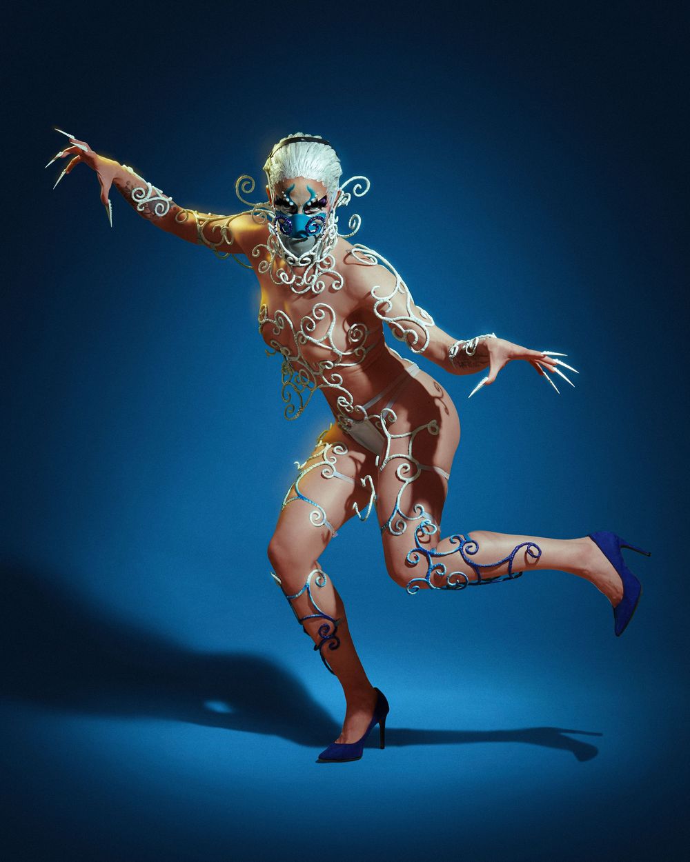 Artistic dance performance with body paint featuring swirling white designs against a deep blue background.
