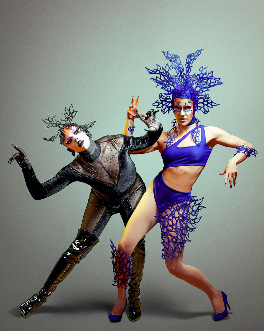 Two dancers perform a dynamic contemporary duet in blue and black costumes against a gray backdrop.