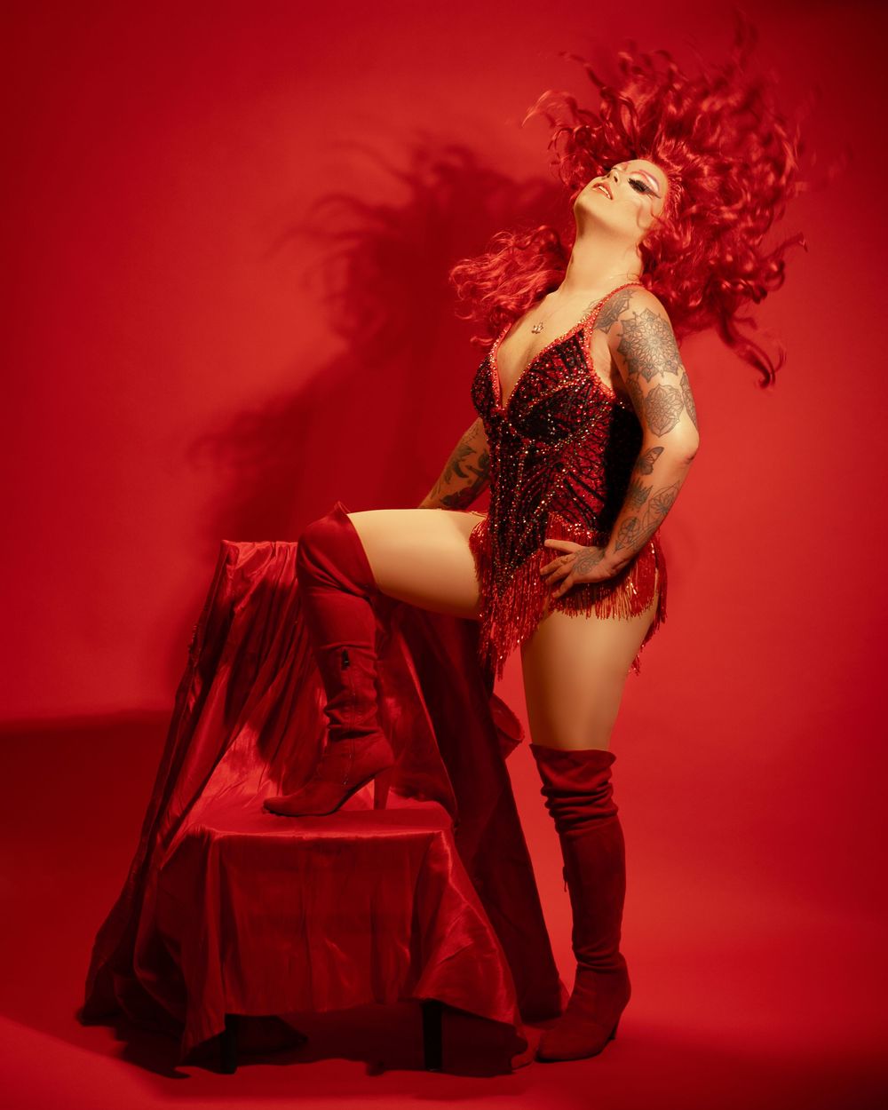 A dramatic fashion photo series with red lighting shows a model in black lingerie posing against a deep crimson background.