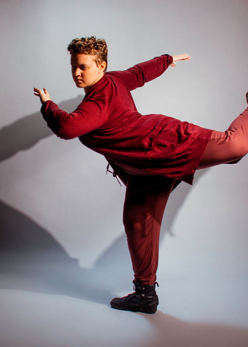 A person in a burgundy outfit performs a graceful dance pose against a white background in a photo sequence.