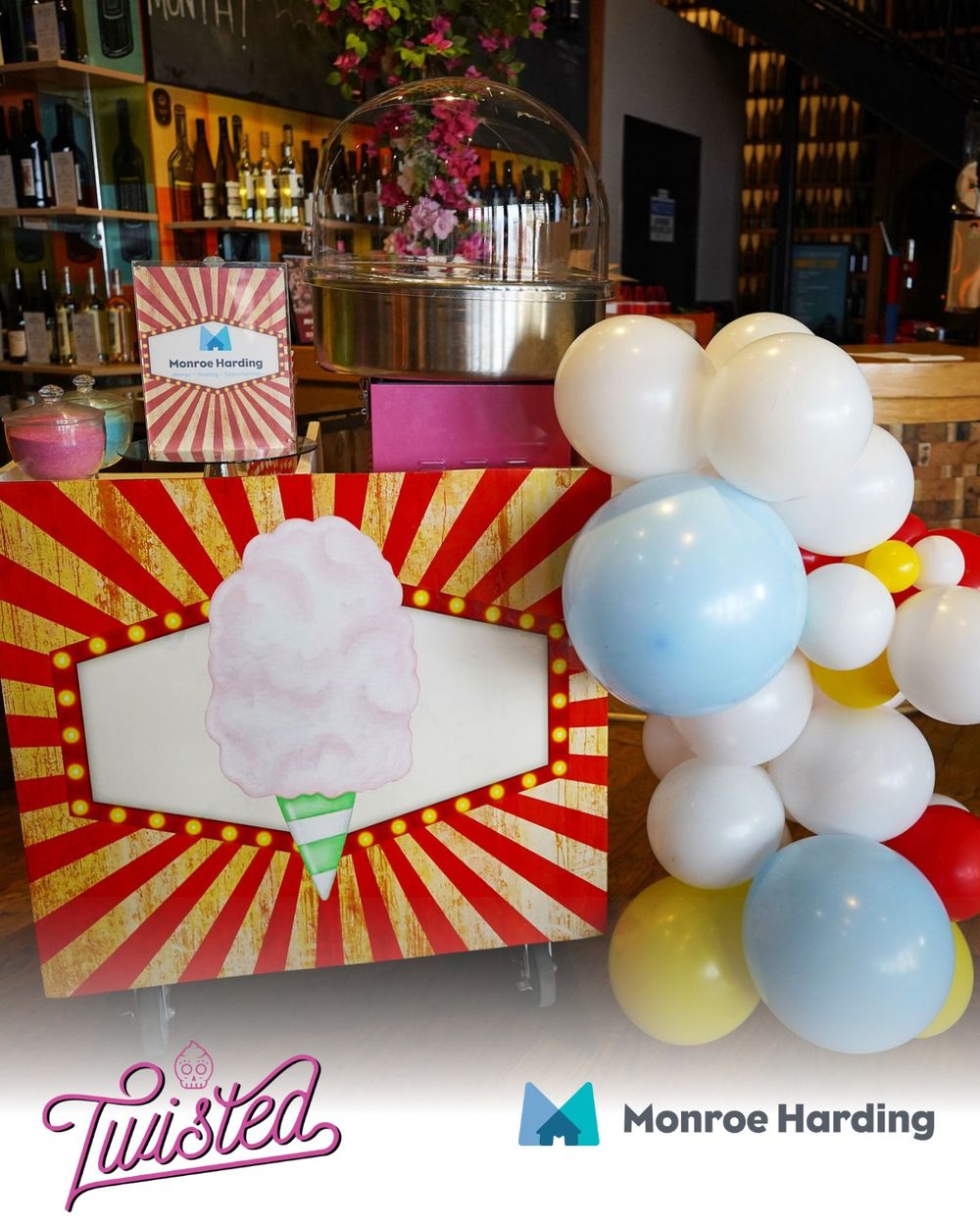Festive event setup with red and white striped decor, balloon arch, and bar display.