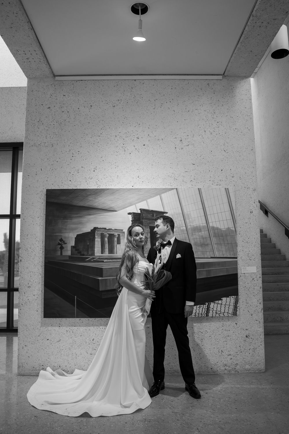Black and white wedding photography sequence showing couple in modern architectural setting with concrete walls and glass.