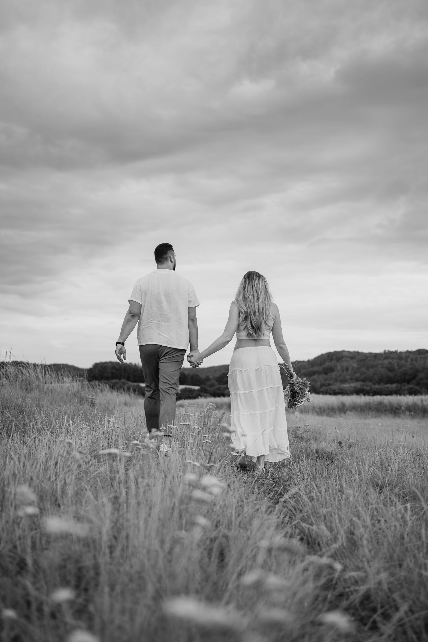 A black and white photo sequence shows a couple walking through a tall grass meadow on their wedding day.