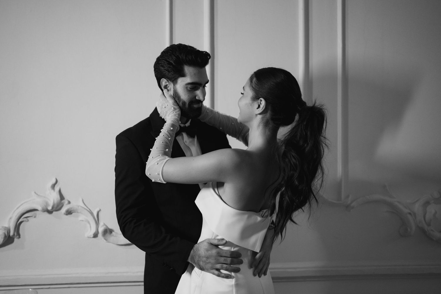 A romantic black and white dance pose captured against an ornate wall.