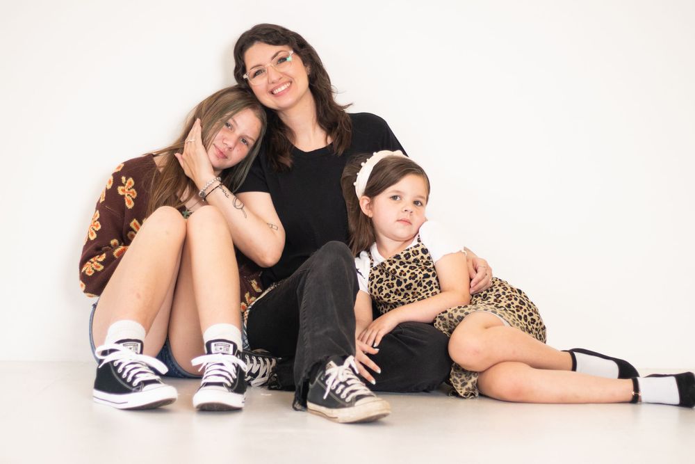 A series of five connected photos showing people sitting and lying on a white floor wearing casual clothing and sneakers.