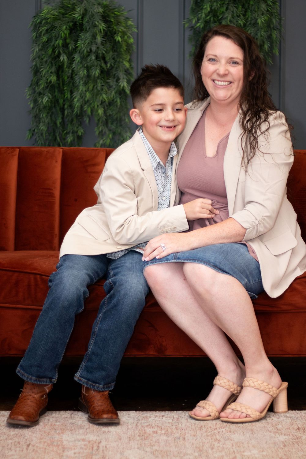 Close-up view of feet and legs sitting on a brown leather couch showing casual footwear and denim.