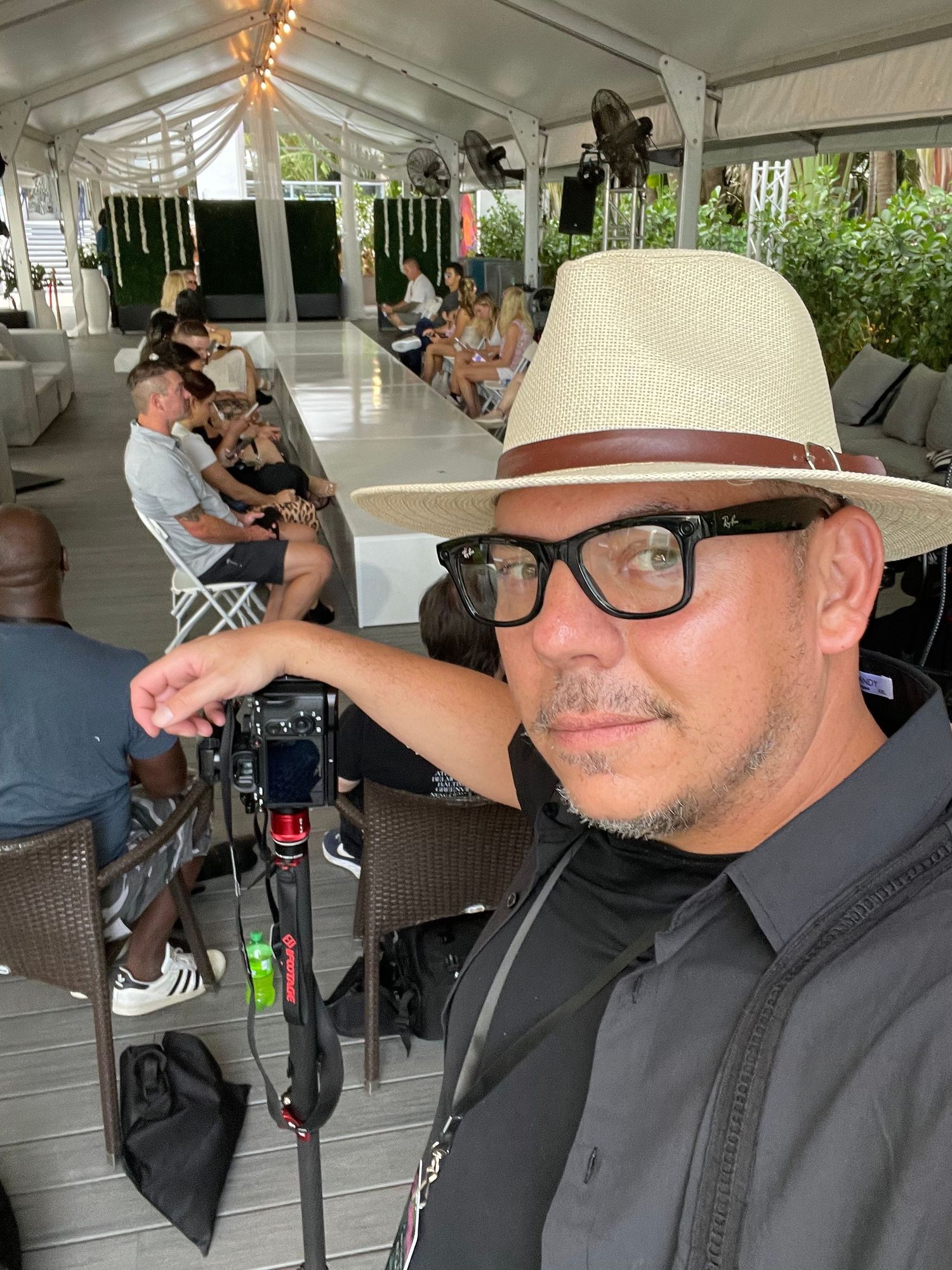Four similar photos of someone wearing glasses and a light colored hat sitting in what appears to be a covered outdoor area.