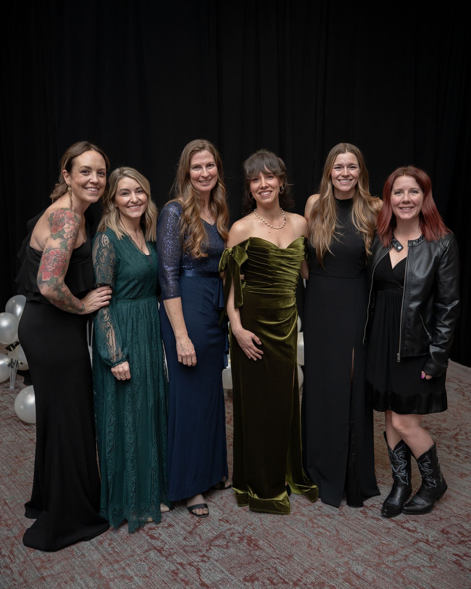 Women in elegant gowns stand close at the formal Valley House Gala fundraising event at Canyon Crest Event Center in Twin Falls, Idaho.