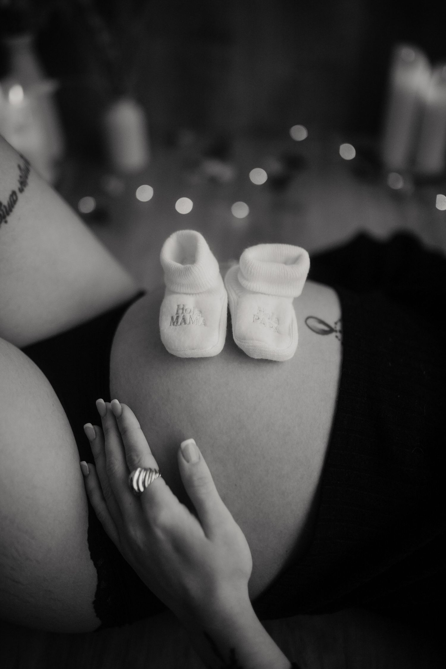 Zapatitos de bebé sobre barriga embarazada en fotografía en blanco y negro
