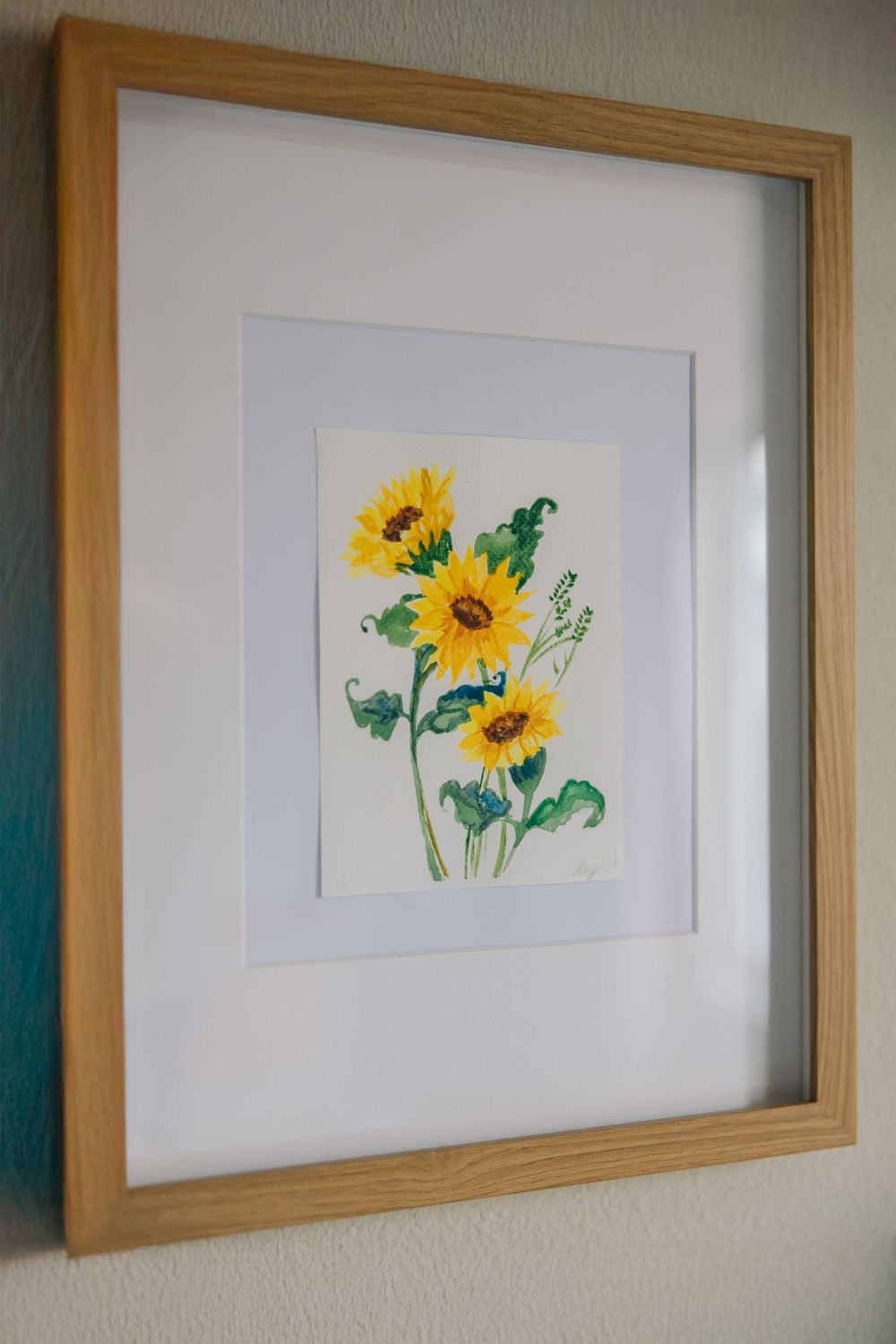 Framed watercolor painting of yellow sunflowers in wooden frame.