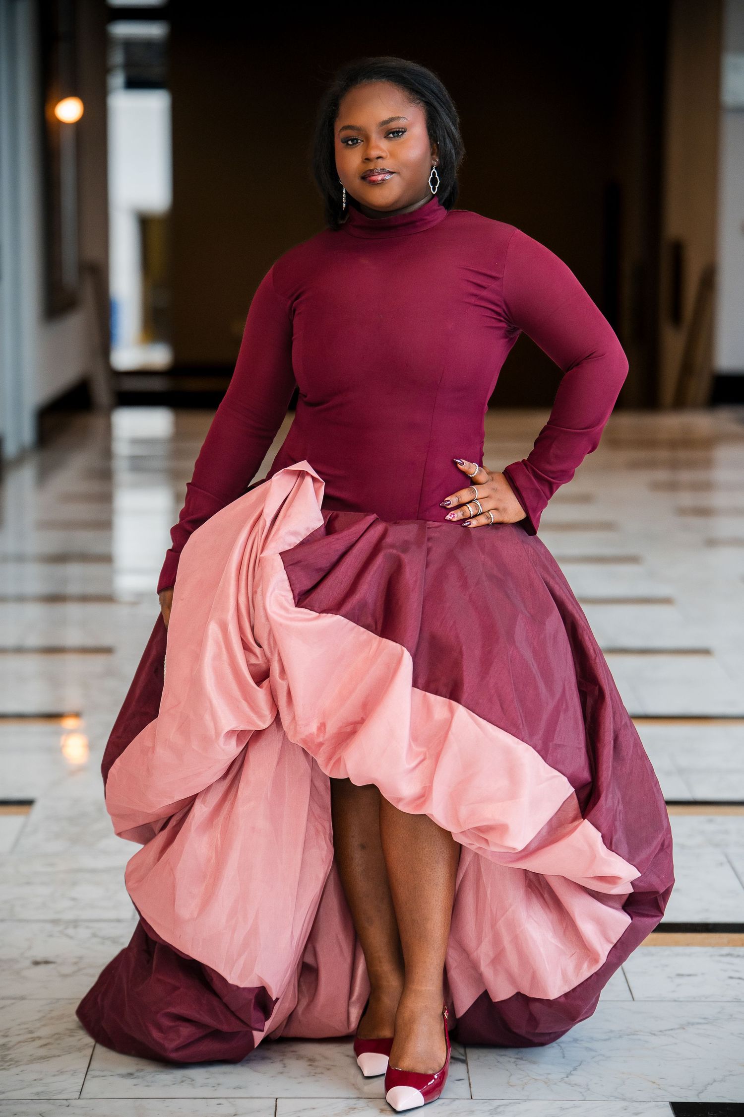 Fashion model poses in burgundy turtleneck and pink skirt showing dynamic movement across multiple frames.