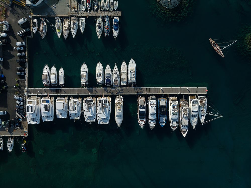 Birds-eye view of boats and yachts lined up in neat rows at a modern marina.
