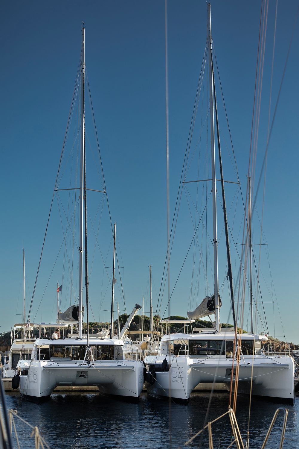 Row of luxury catamarans moored at a marina dock against clear blue sky on a sunny day.