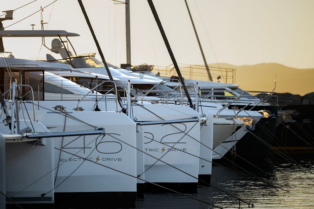 Luxury yachts and boats moored at a marina during golden sunset with warm lighting.