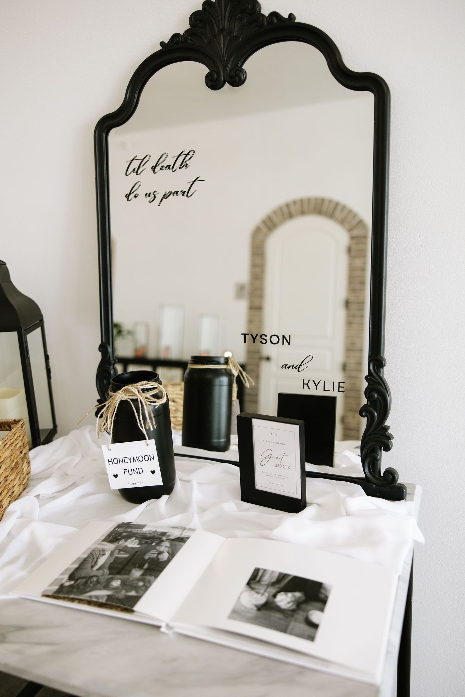 Elegant black vintage mirror with wedding details and photos displayed on white surface.
