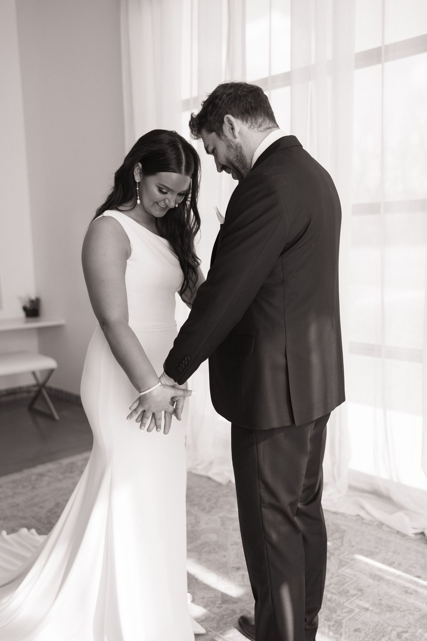 A black and white photo of a couple sharing an intimate moment in wedding attire.