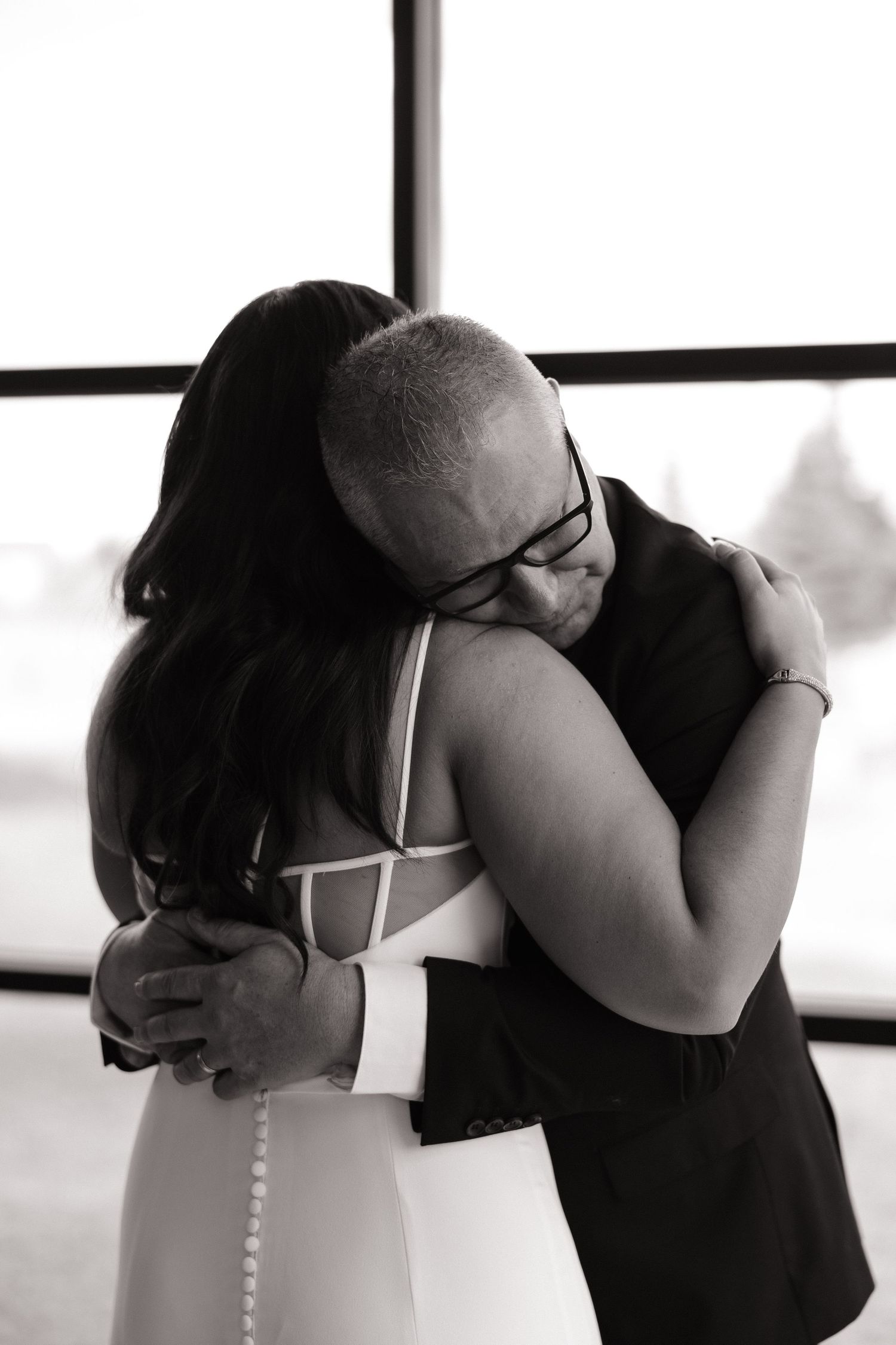 An emotional black and white photograph capturing an intimate embrace during a wedding ceremony.