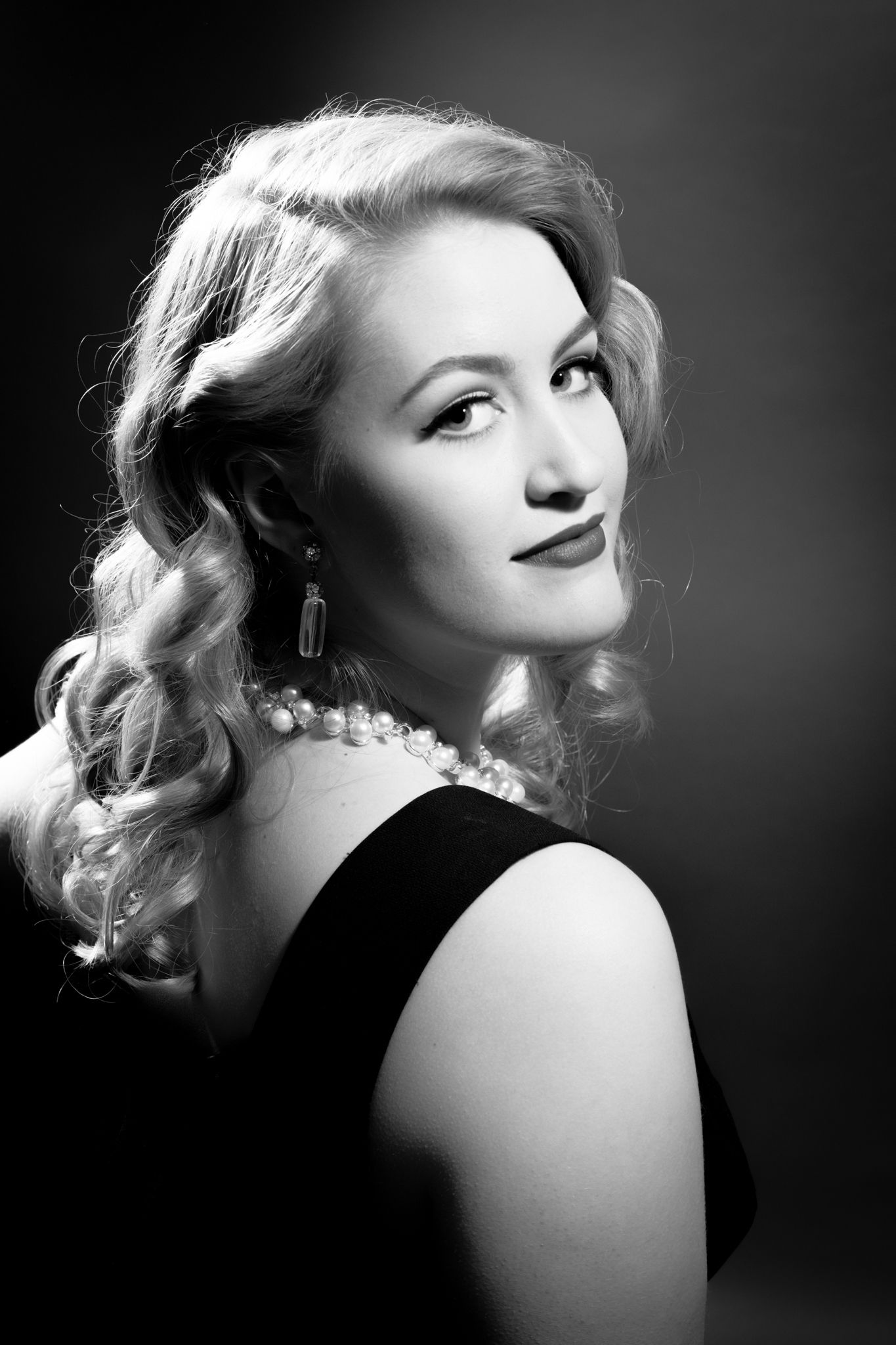 Classic Hollywood glamour portrait in black and white with pearl necklace.