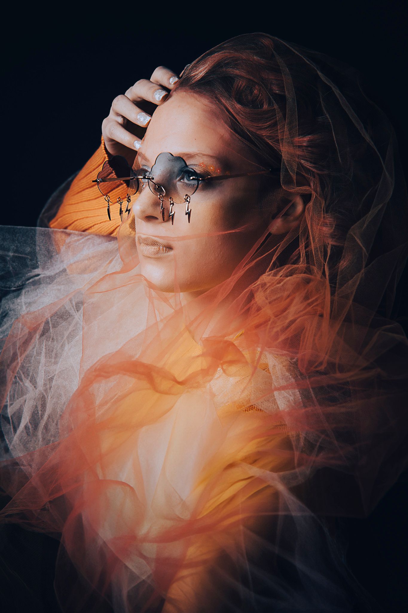 Artistic portrait with orange smoke effects and decorative glasses against dark background.