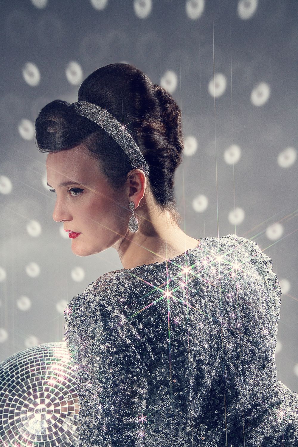 A glamorous portrait with sparkly sequined dress against a backdrop of glowing circles.