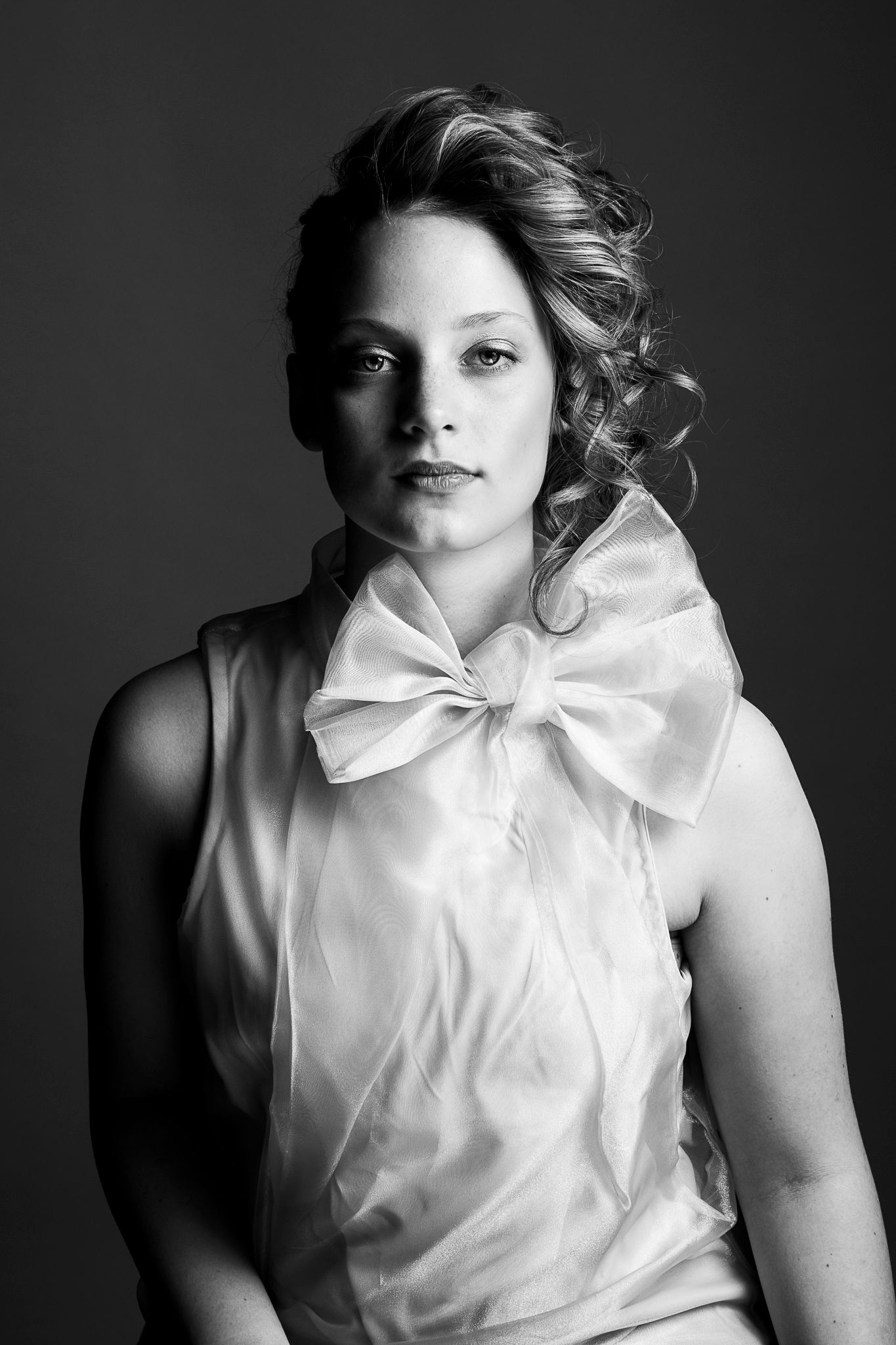 Black and white portrait featuring a white blouse with an oversized bow detail.