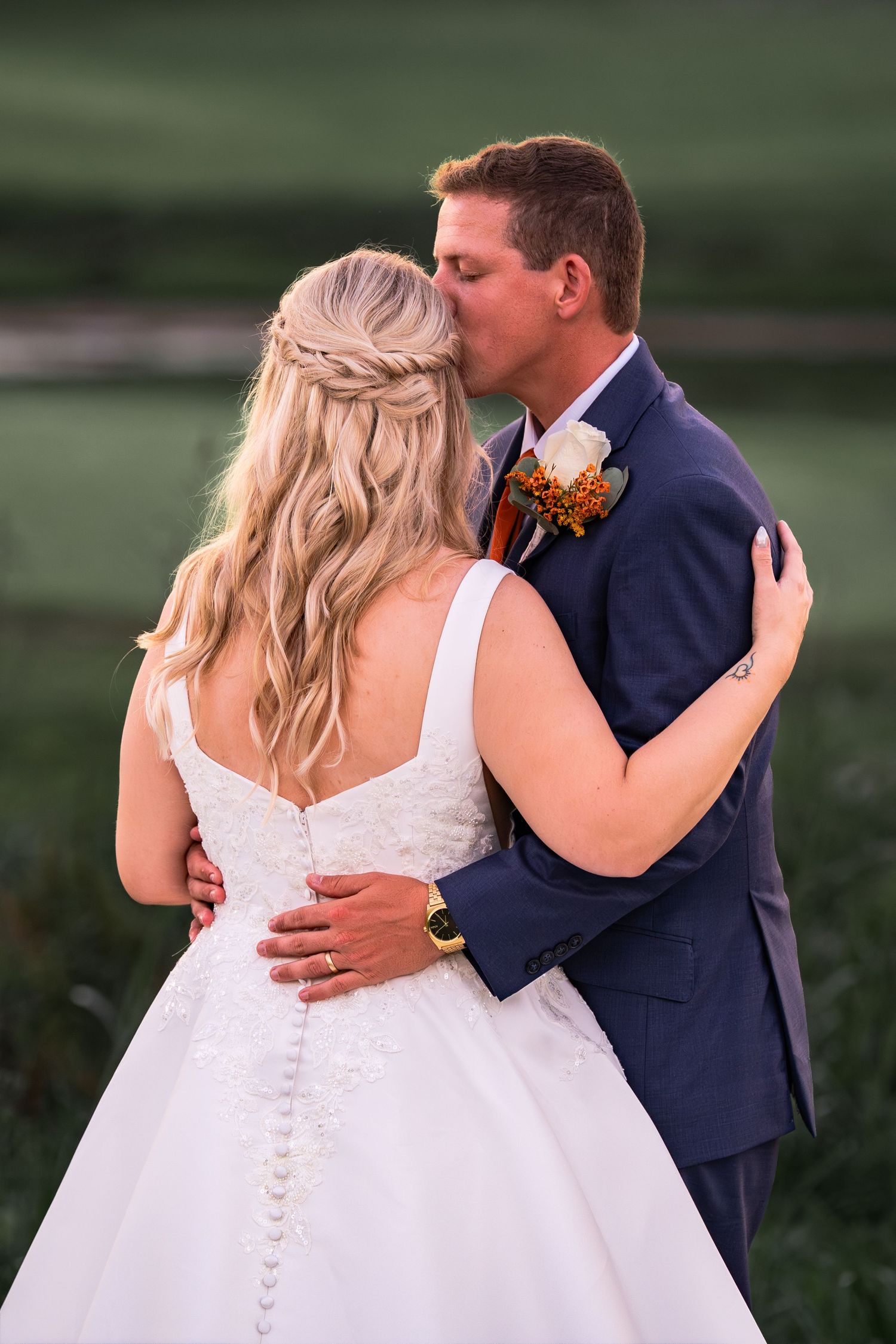Romantic wedding couple embraces in navy suit and white dress during outdoor sunset photo session.