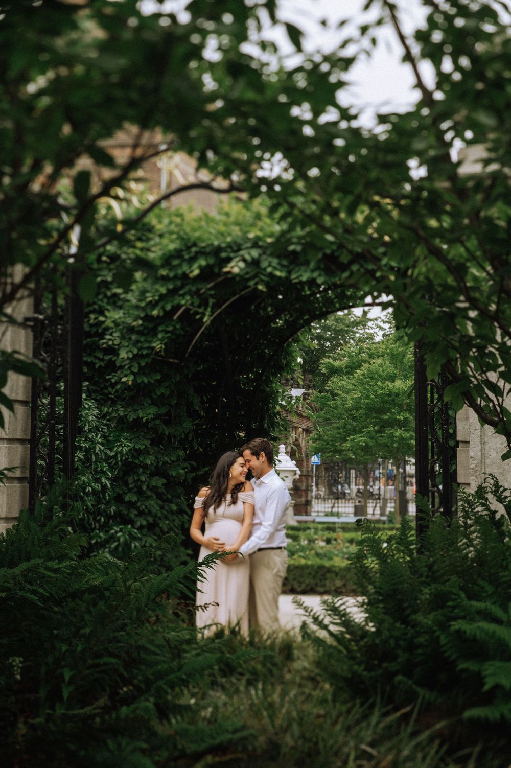 Maternity photoshoot in Amsterdam park — couple hugging in the sunlight